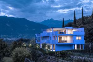 a blue house on a hill with mountains in the background at Penthouse & Garden - luxury apartment in Postal
