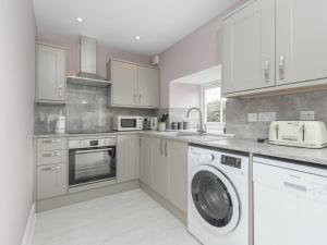 a kitchen with white cabinets and a washer and dryer at The Forge in Morpeth