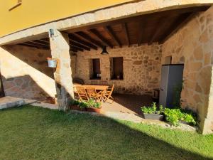 un patio con mesa y sillas bajo un edificio de piedra en Casa Rural El Caño de Abajo, en Aldeanueva del Camino