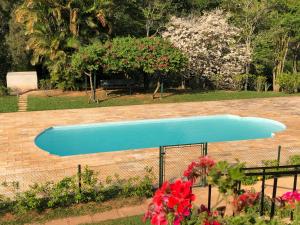 a blue swimming pool in a yard with flowers at Pousada Gardenian in São Roque