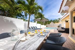 Jan Thiel的住宿－Villa Drumi Dushi，一个带游泳池的庭院里的一张木桌和椅子
