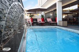 a swimming pool with a water feature next to a building at Indaba Lodge Gaborone in Gaborone