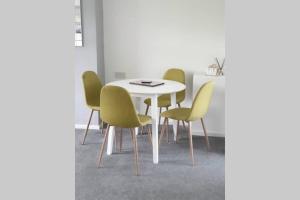 a dining room with a white table and yellow chairs at Stay Newbiggin-By-The-Sea in Woodhorn