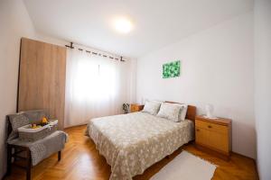 a bedroom with a bed and a chair and a window at Apartman Jadranka in Zadar