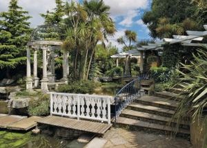 a garden with a gazebo and stairs and a pond at Foxhunter Park in Minster