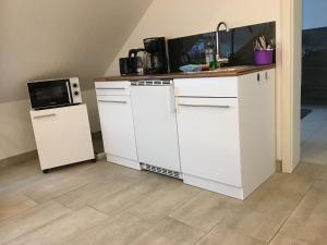 a kitchen with white cabinets and a microwave and a refrigerator at H&E Apartments in Steinheim
