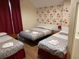 ein Zimmer mit 3 Betten und Handtüchern darauf in der Unterkunft Abbey Lodge Hotel in London