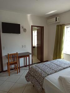 a bedroom with a bed and a desk and a television at Iria's Hotel in Timbó
