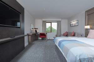 a hotel room with a bed and a flat screen tv at McWilliam Park Hotel in Claremorris