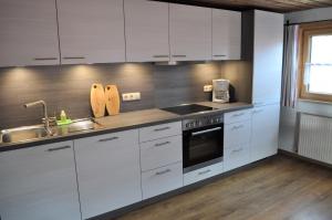 a kitchen with white cabinets and a sink at Ferienwohnung Baumgartner in Bad Hindelang