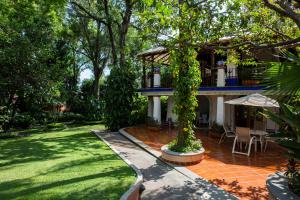 ein Haus mit einem Garten und einer Terrasse mit einem Sonnenschirm in der Unterkunft Hotel Spa Posada Tlaltenango in Cuernavaca