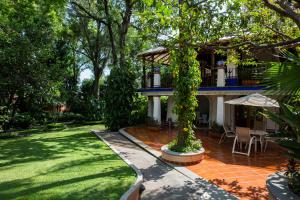 a house with a garden and a patio with an umbrella at Hotel Spa Posada Tlaltenango in Cuernavaca