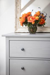 a vase of flowers on a dresser with a mirror at Blossom Hill Apartments in Łęcze