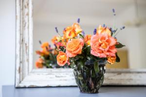 a vase of orange flowers in front of a mirror at Blossom Hill Apartments in Łęcze