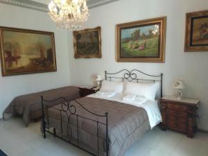 a bedroom with two beds and paintings on the wall at PEDRA HOUSE in Catania