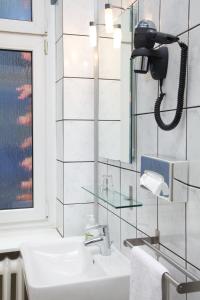 ein Badezimmer mit einem Waschbecken und einem Telefon an der Wand in der Unterkunft ArtHotel Connection in Berlin