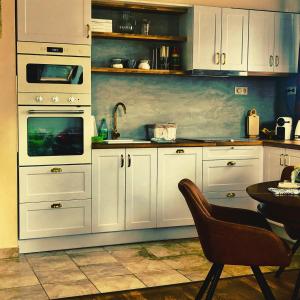 uma cozinha com armários brancos e uma mesa com uma cadeira em Birdland Apartman em Bük