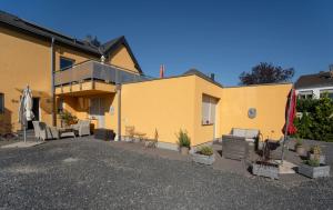 海因斯貝格的住宿－Ferienwohnung Anke 5，黄色的建筑,配有椅子和庭院