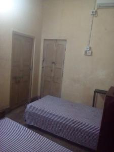 Cette chambre comprend 2 lits et 2 portes. dans l'établissement APRO, à Kolkata