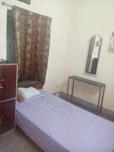 - une petite chambre avec un lit et un miroir dans l'établissement APRO, à Kolkata