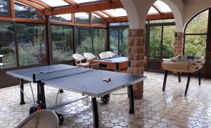 - une table de ping-pong dans une pièce avec fenêtres dans l'établissement Logis La Rose Des Vents, à Volvic