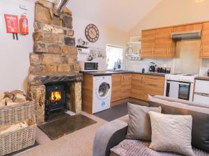 a living room with a stone fireplace in a kitchen at Dovecote Cottage in Scarborough