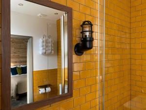 a mirror on a yellow tiled wall in a bathroom at The Southern Belle in Brighton & Hove