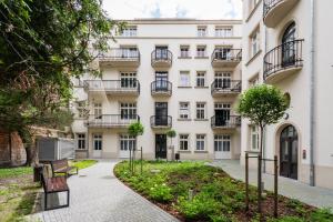 an apartment building with benches in front of it at Groble Deluxe Apartments WAWELOFTS in Krakow