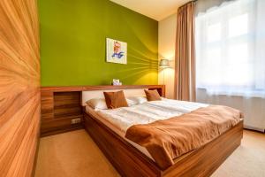 a bedroom with a bed with a green wall at Černý Orel – Pivovar, Čokoládovna a Wellness Hotel in Kroměříž