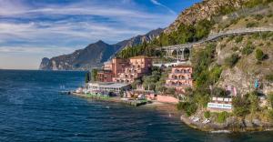 a town on the side of a mountain next to the water at Hotel Capo Reamol in Limone sul Garda