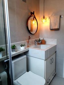 a bathroom with a white sink and a mirror at APARTAMENTO PRAIA GRANDE-CANTO DO FORTE- 2 QUADRAS DA PRAIA WI-FI,NETFLIX e ESTACIONAMENTO in Praia Grande