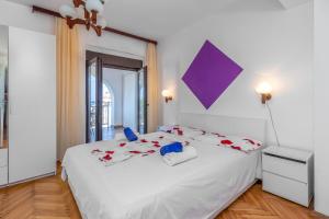 a bedroom with a large white bed with red pillows at Maestral Apartments in Malinska