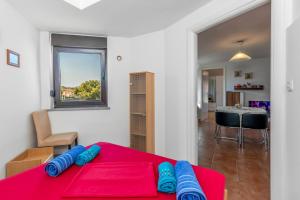 a room with a red table with blue pillows on it at Maestral Apartments in Malinska