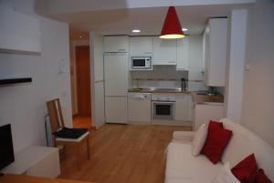 a living room with a white couch and a kitchen at TU APARTAMENTO EN EL VALLE DE TENA en ESCARRILLA in Escarrilla