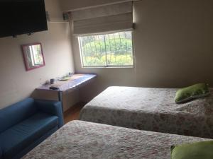 1 dormitorio con 2 camas, lavabo y ventana en Habitaciones en Buena Vista, en Lima