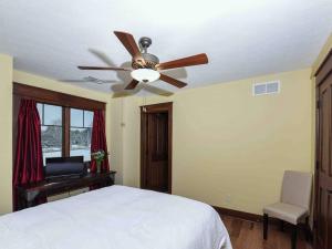 Schlafzimmer mit Deckenventilator und Schreibtisch in der Unterkunft Purple Skies Homestead in North Royalton