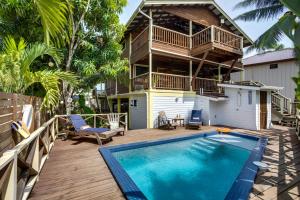 a house with a swimming pool and a balcony at Driftwood Gardens Guesthouse in Placencia