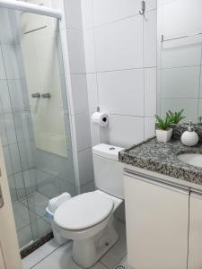 La salle de bains blanche est pourvue d'une douche et de toilettes. dans l'établissement Flat Porto de Galinhas, à Porto de Galinhas