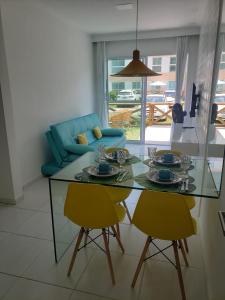 - un salon avec une table en verre et deux chaises jaunes dans l'établissement Flat Porto de Galinhas, à Porto de Galinhas