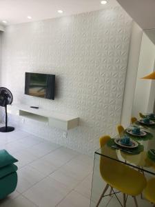 - un salon avec une table et une télévision murale dans l'établissement Flat Porto de Galinhas, à Porto de Galinhas