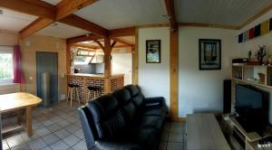 a living room with a black leather couch and a television at chalet avec vue imprenable in Bagnères-de-Bigorre