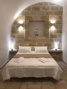 1 dormitorio con 1 cama grande y pared de piedra en Casetta dello Scrittore, en Ostuni