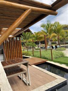 a wooden deck with a bench next to a pool at La Fleur Polinésia in Porto De Galinhas