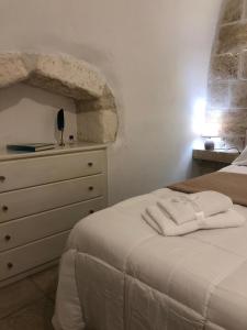 a bedroom with a white bed and a dresser at Casetta dello Scrittore in Ostuni