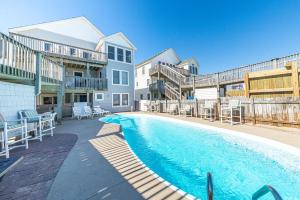 a swimming pool with chairs and a building at Paradise Found in Nags Head