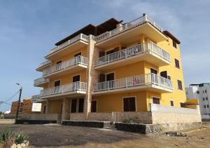 a yellow building with white balconies on it at Pedra do Sol Praia Estoril Sal Rei FREE WI-FI in Sal Rei
