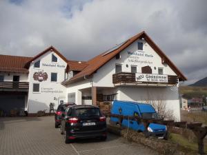 ein weißes Gebäude mit davor geparkt in der Unterkunft Weinhotel Kienle in Burrweiler