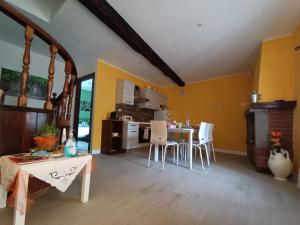 cocina con paredes amarillas, mesa y sillas en B&B Il Grifo, en Bomarzo