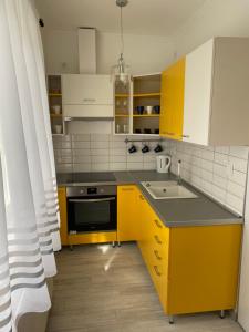 a kitchen with yellow cabinets and a sink at City Center Apartman Nagykanizsa in Nagykanizsa