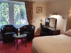 a hotel room with a bed and two chairs and a mirror at Stow Lodge Hotel in Stow on the Wold
